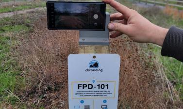 Photo of a phone taking a picture of Orchard glen park on a chronolog photo station