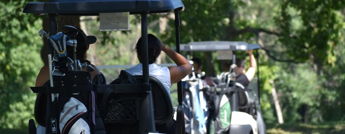 Photo of women riding in golf cart on golf course