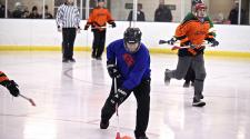 This image shows one guy trying to get the ball up the ice and teammates following during adult broomball.