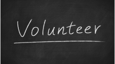 This image shows the word volunteer written on a white board.