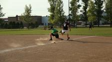 This image shows someone running to first base and the first baseman catching the ball during adult softball league.
