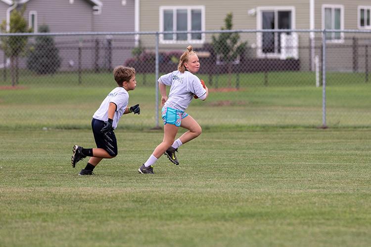flagfootballyouth4 This image shows a girl running with the football and a boy following her at the youth football program.