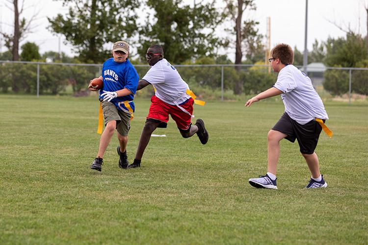 flagfootballyouth3 This image shows a boy carrying a football and running from two boys at the youth football program.