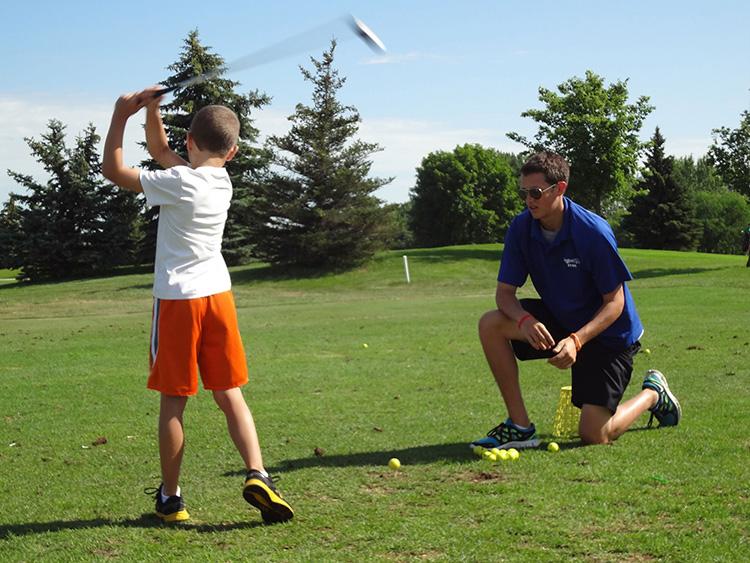 golfyouth This image shows the coach helping a boy during youth golf lessons.