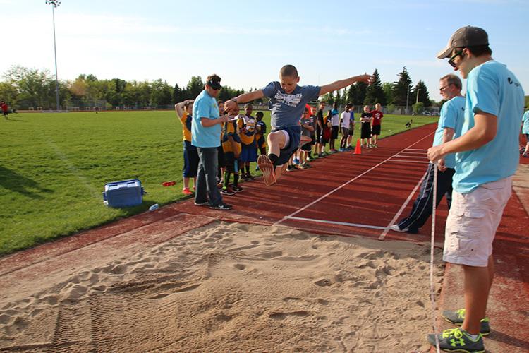 This image shows a boy doing the long jump during the track and field program.