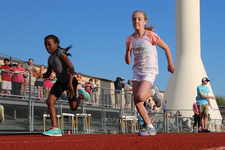 This image shows two girls racing during a track and field program.