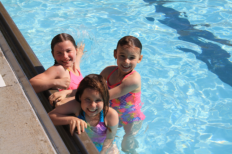 This image shows three girls swimming in a pool.