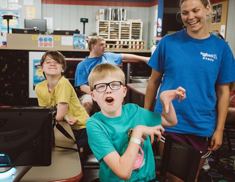 This image shows two boys and an instructor posing for the camera during the youth adaptive summer camp.