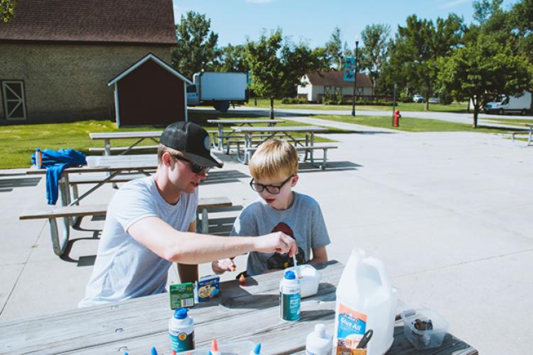 This image shows a boy and instructor making a craft during the youth adaptive summer camp.