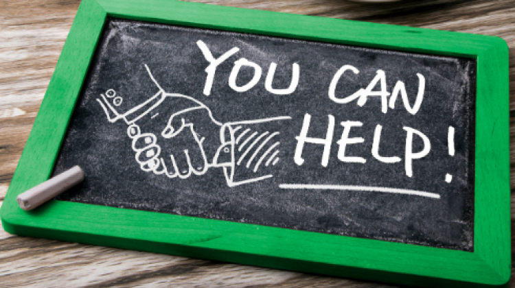 This image shows a you can help sign on a table.