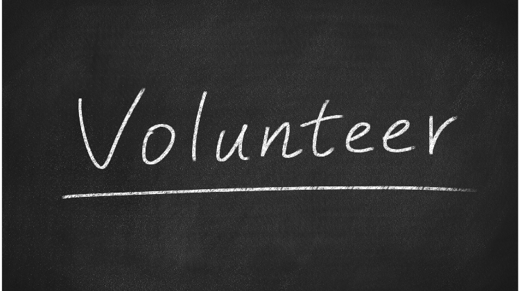 This image shows the word volunteer written on a white board.