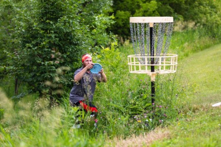 This image shows a male about to throw his frisbee into the disc golf basket.