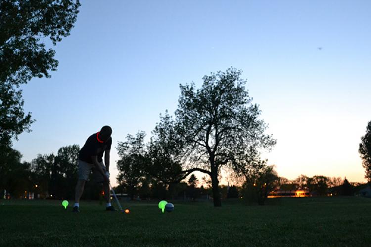 This image shows a male getting ready to tee off at Glow Golf.