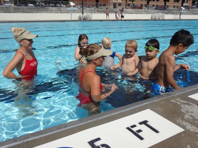 This image shows two femaile lifeguards teaching kids to swim.