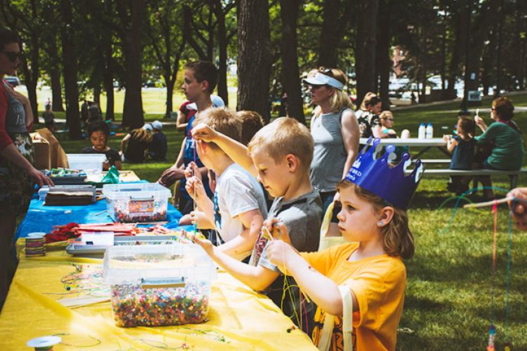This image shows some kids making crafts at a table during Midwest Kids Fest.