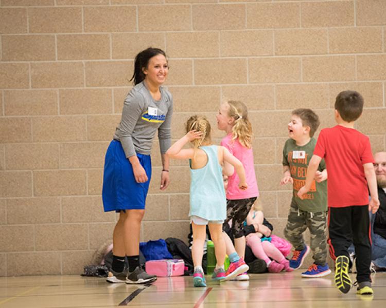 This image shows a group of kids running to the instructor at the sports sampler.