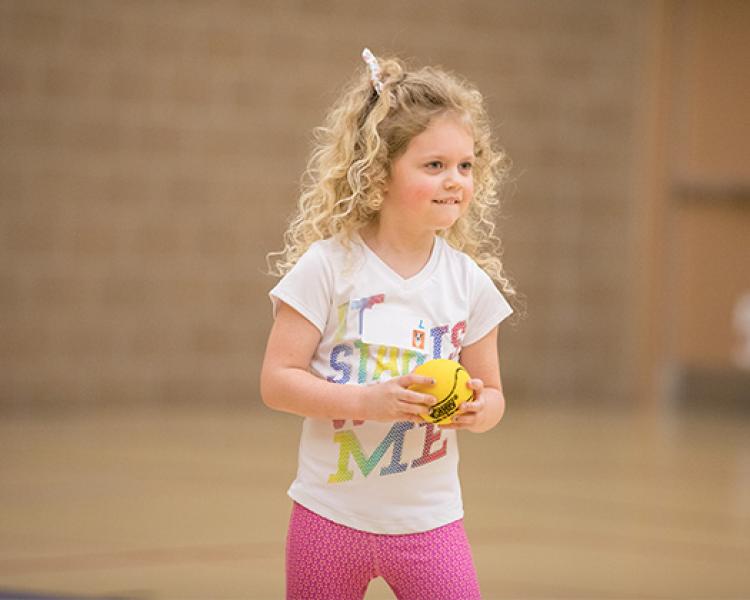 This image shows a girl holding the ball at sports sampler.