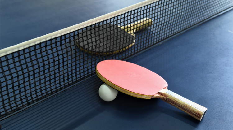 This image shows table tennis paddles and the ball on the table tennis table.