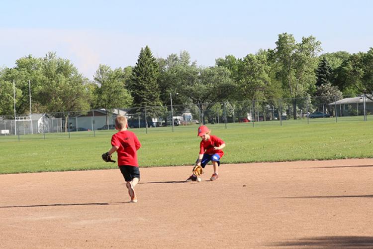 This image shows a boy fielding the ball during the youth tee-ball program.