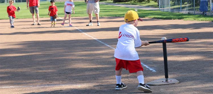 This image shows a boy hitting the ball at the youth tee-ball program.