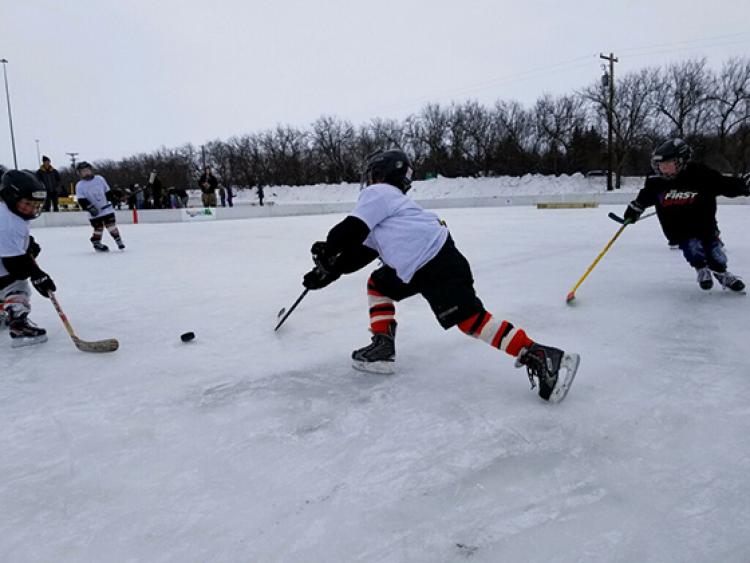 youthpondhockey This image shows two players chasing the puck at youth pond hockey.