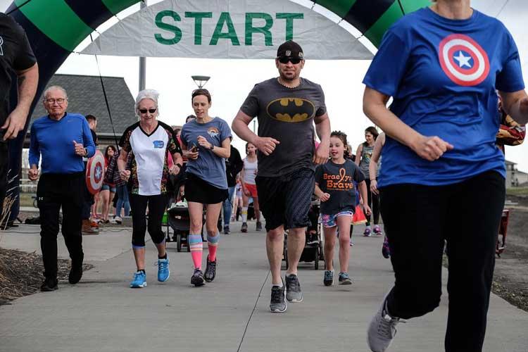 Photo shows runners leaving the starting line of 5k run.