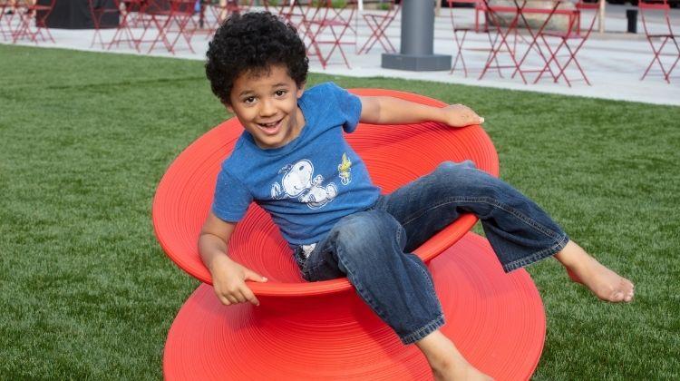 broadwaysquaresummer This image shows a young boy on the spin chairs at Broadway Square.