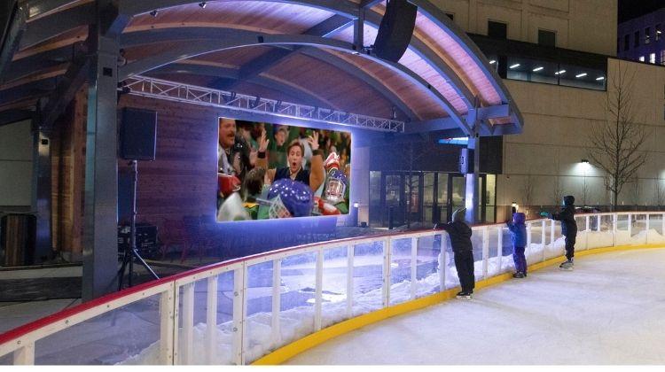 This image shows three young kids standing on SCHEELS Skating Rink watching a movie during the Rink Reels event.