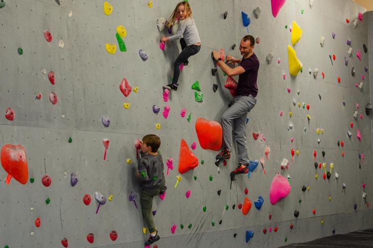 two youth climbing on rock wall with instructor