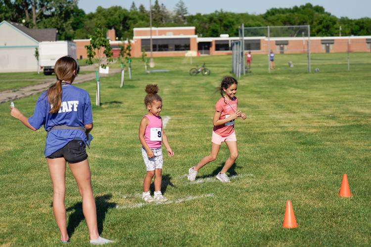 Kids Triathlon - Kids ready to race two kids at the starting line for race event in grass field for kids triathlon with Staff member calling go