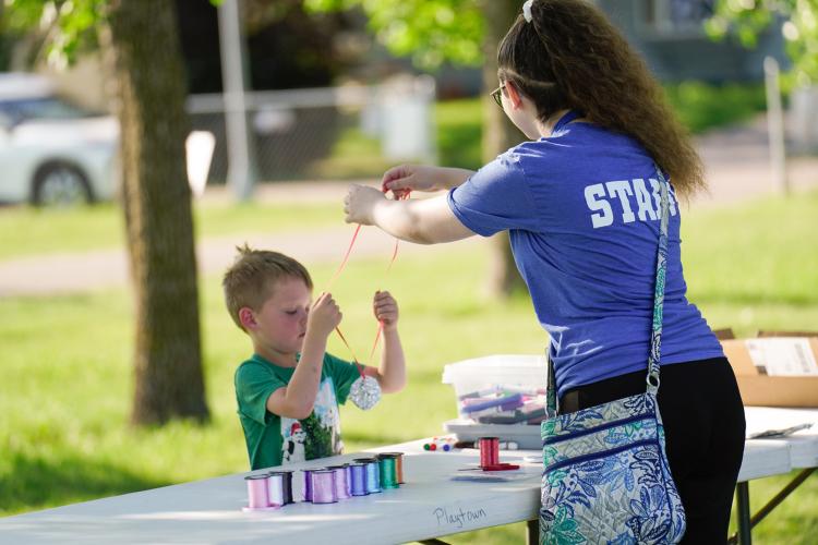 Kids Triathlon - Making Medal Kid making a medal for his award at craft table with staff member assisting
