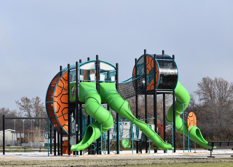2-Story Playground with 3 green slides, a climbing structure, a swing set and a rope bridge