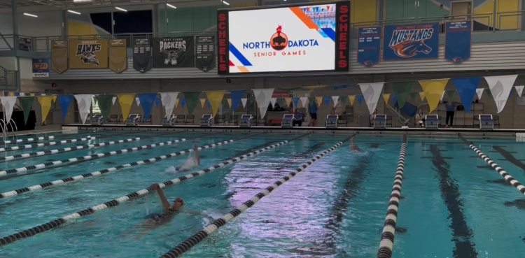 Swimming at ND Senior Center.png three people swimming at Hulbert Aquatics Center doing the backstroke