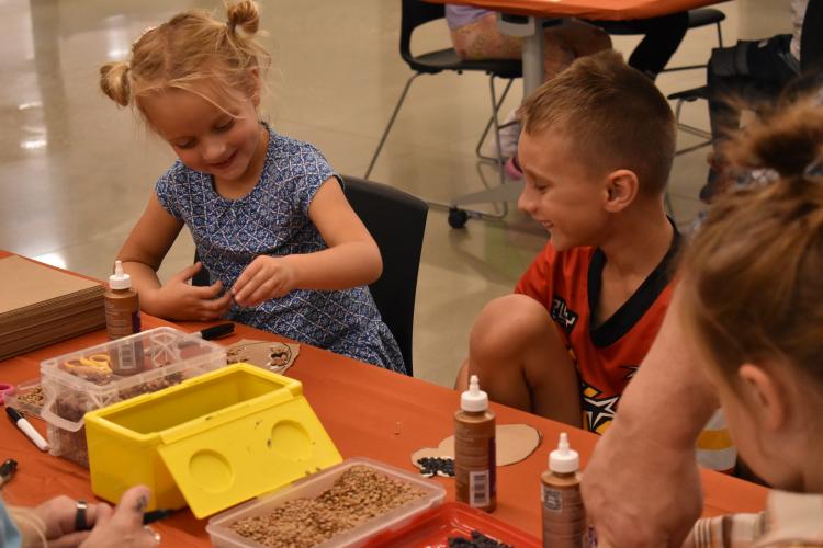 Young girl and boy smiling doing crafts at a table.