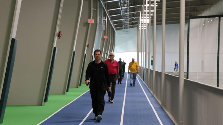 Walking Club Program 2.png Several Adults walking on the indoor walking track at the Fargo Parks Sports Center.
