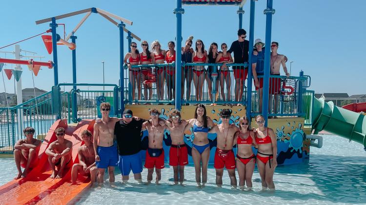 Lifeguards at the Davies Outdoor Pool standing on the aquatic playground lined up for a picture.