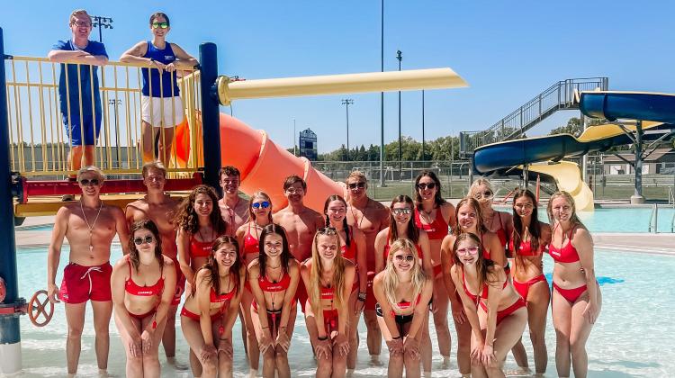 Lifeguards at the Roger E. Gress Northside Outdoor Pool standing on the aquatic playground lined up for a picture.