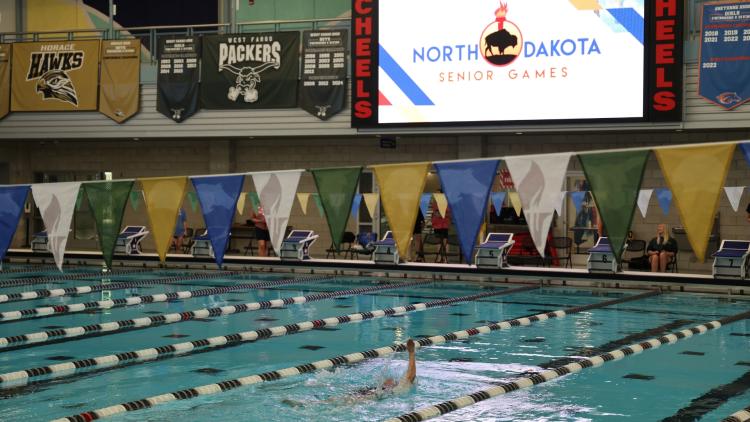 This image shows a swimmer competing in a lane during an indoor swimming event at the North Dakota Senior Games.