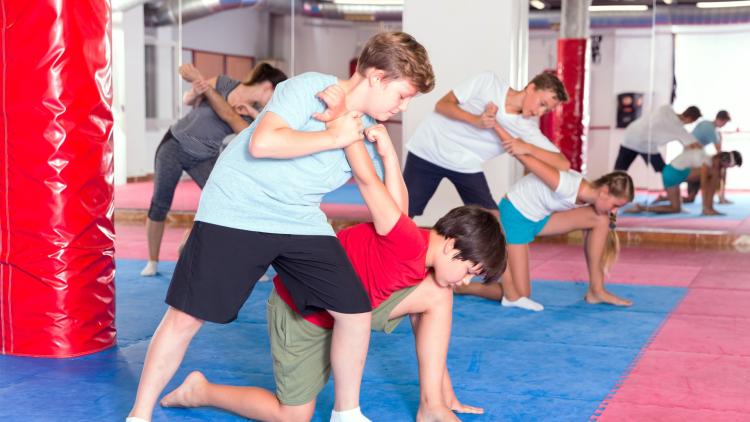 Youth work in pairs to practice self-defense holds and techniques during class.