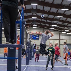 This image shows a male volleyball player spiking the ball./ 