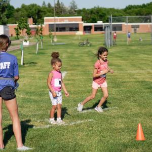 two kids at the starting line for race event in grass field for kids triathlon with Staff member calling go