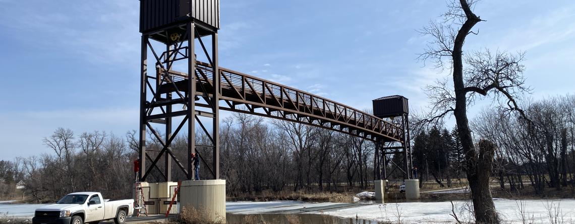 This image shows Fargo Park District employees raising the Lindenwood pedestrian bridge