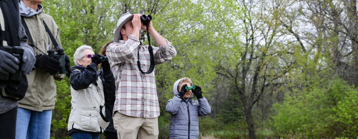 Picture of 5 people looking through binoculars in a forest