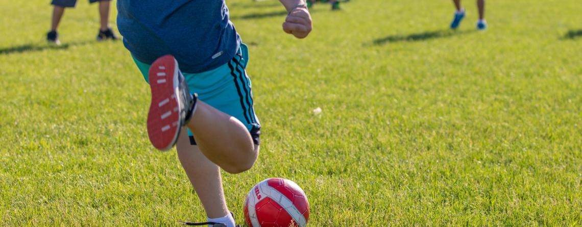 Kid kicking soccer ball in park