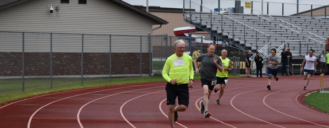 three men running in track event