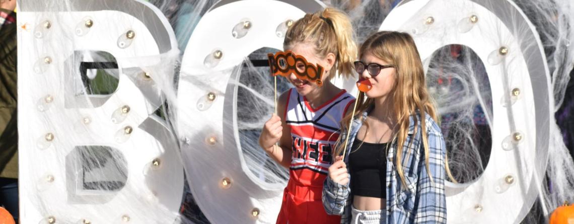 Two girls pose in front of Boo sign