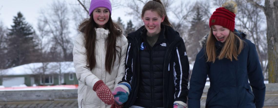 Photo of three girls ice skating at outdoor skating rink