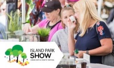 This image shows a woman smelling something at Island Park Show. 