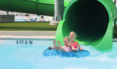 two young girls coming out of the green tube slide at Island Park Pool 