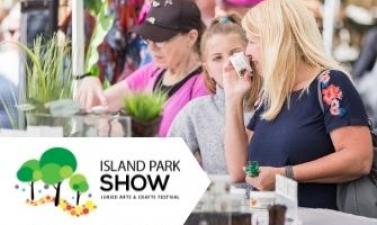 This image shows a woman smelling something at Island Park Show.